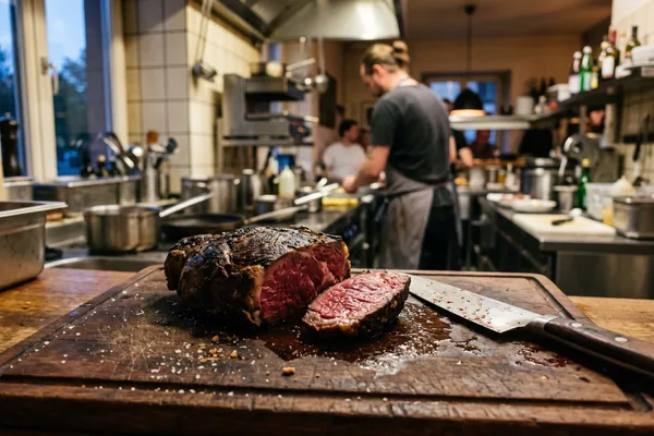 Angeschnittenes Steak auf einem Holzbrett in einer Restaurantküche am Abend