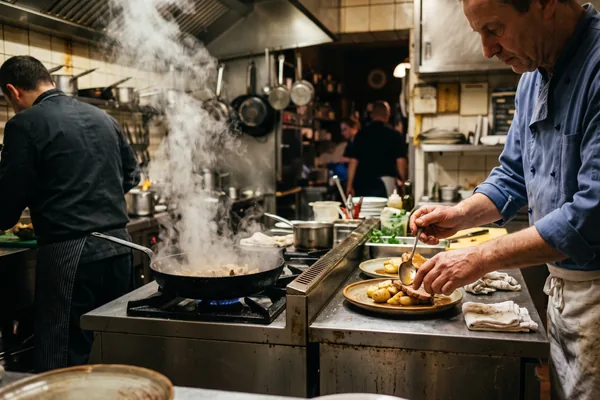 Kochhände am Pass einer kleinen Restaurantküche während des Service